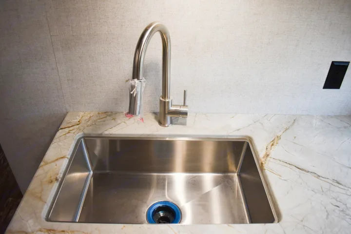 Sleek stainless steel sink with pull-down faucet and marble countertop in a bright RV rental kitchen.. Starcraft Travel Trailer 2020