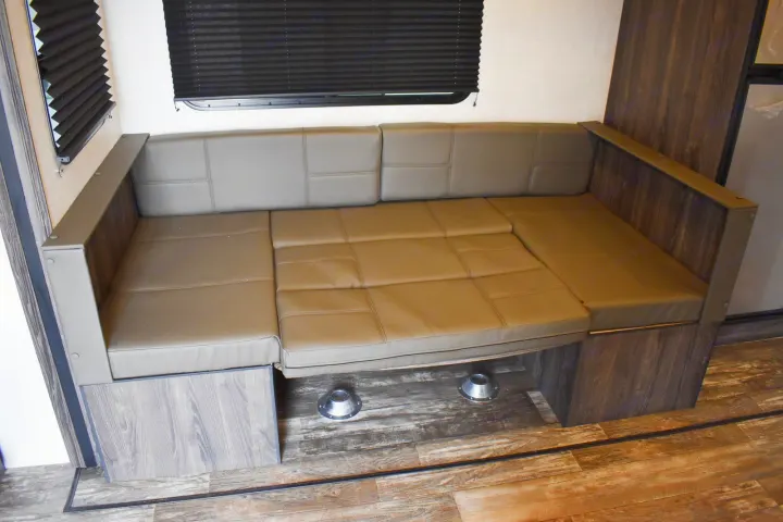 An RV rental's clever interior: a tan sofa/dinette converts to a bed, maximizing space with blinds and wood-look floor.. Starcraft Travel Trailer 2020