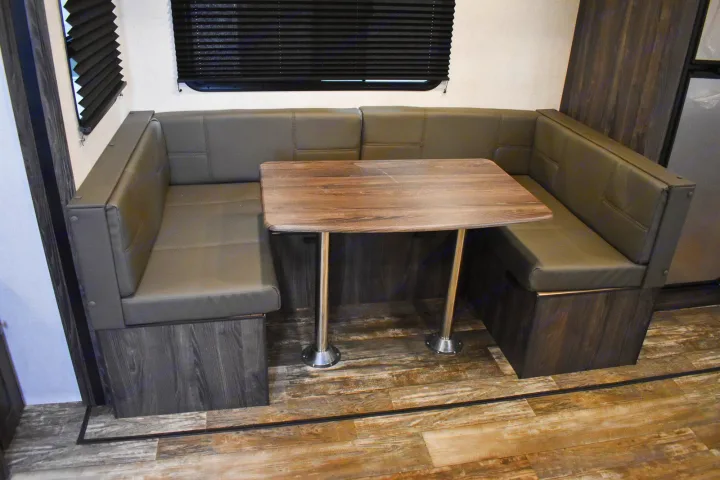 Cozy RV rental dinette with U-shaped gray seating and a wood table, featuring dark wood accents.. Starcraft Travel Trailer 2020