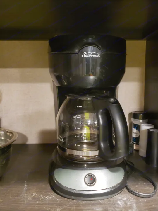 Black Sunbeam coffee maker, active with red light, on dark counter in an RV rental kitchen. Ready for morning coffee.. Forest River XLR hyperlite 2019