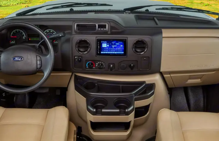 Detailed RV rental interior: Ford E-Series cockpit with dashboard, infotainment, climate controls, and ample storage for your journey.. Jayco Class C Motorhome 2019
