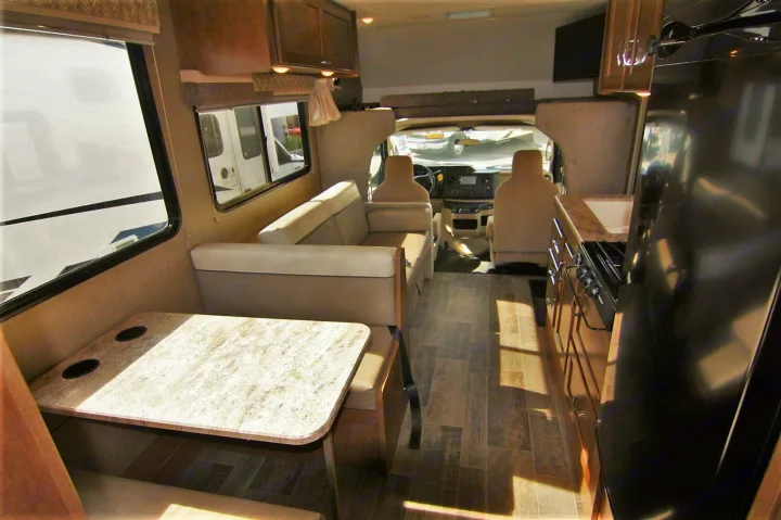 RV rental interior showcasing a cozy dinette, sofa, functional kitchen, and driver's cockpit. Ready for adventure!. Winnebago Outlook 2019