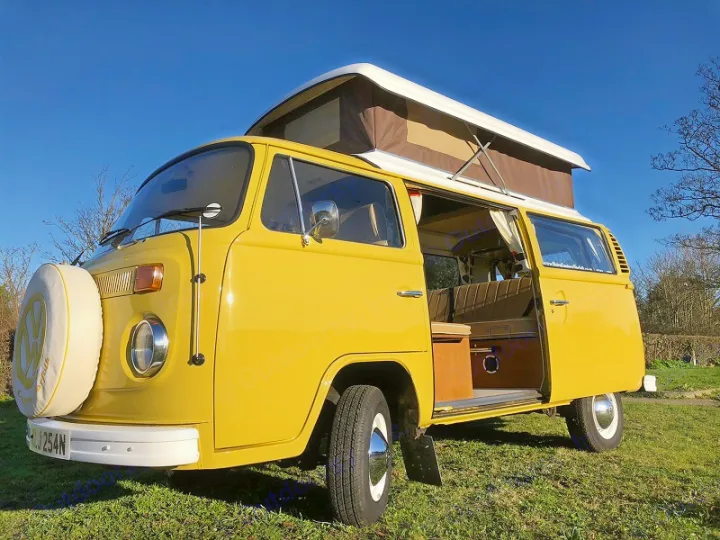 A vibrant yellow VW T2 campervan with an extended pop-top roof and open side door, perfect for an rv rental adventure.. Volkswagen 2.0L T2 Late Bay 1975