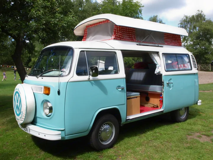 This light blue and white vintage VW camper van with an extended pop-top and open door showing its interior is ideal for an rv rental.. Volkswagen 2.0L T2 Late Bay 1975