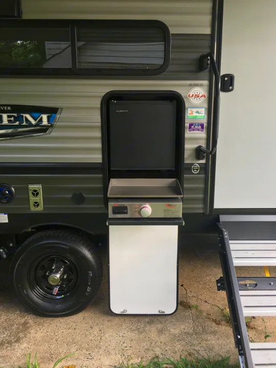 Side view of an RV rental with its outdoor kitchen, featuring a Suburban griddle and Furrion refrigerator, ready for camping.. Forest River Salem 2021