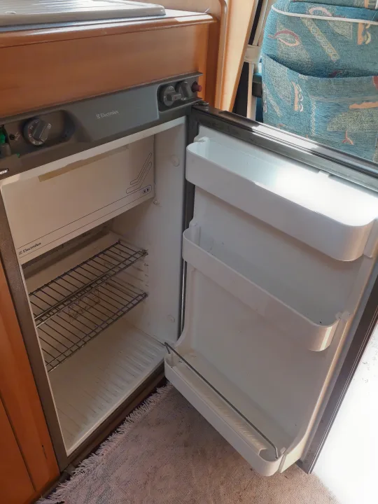 Clean, empty Electrolux refrigerator in an RV rental, revealing wire shelves & door compartments. Ready for groceries!. Fiat Ducato Swift Suntor 2000