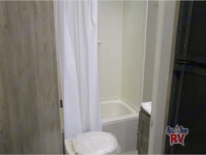 This RV rental features a compact bathroom with a white shower-tub combo, toilet, and vanity cabinet.. Dutchmen Aspen Trail 2019