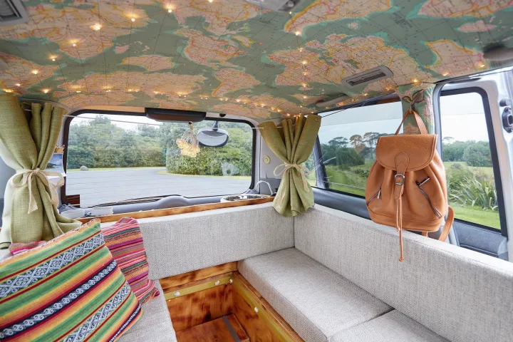 Cozy RV rental interior with a unique map-covered ceiling, string lights, comfy seating, sink, and scenic outdoor views.. Toyota Voxy 2007