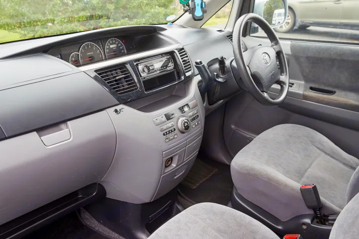 Inside a spacious **RV rental**, highlighting the grey dashboard, central console, and front seating area.. Toyota Voxy 2007