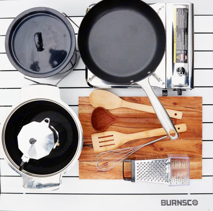 Camping stove, pan, pot, Moka pot, and utensils for an RV rental outdoor kitchen, neatly arranged on a white table.. Toyota Voxy 2007
