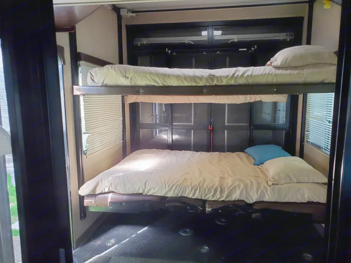 Two-level bunk beds in an RV rental, with light bedding, windows, and blinds for cozy sleeping.. Heartland Cyclone 2014
