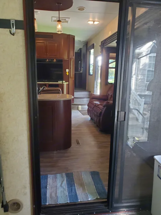 Inside a bright RV rental: modern kitchen island, wood floor, comfy leather sofa, and screen door to outside views.. Heartland Cyclone 2014