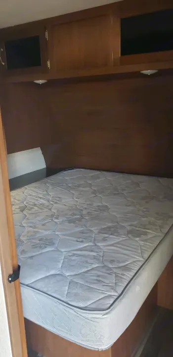 RV rental bedroom: A white patterned mattress on a built-in bed, with wooden overhead cabinets for storage.. Jayco Jay Flight 2019