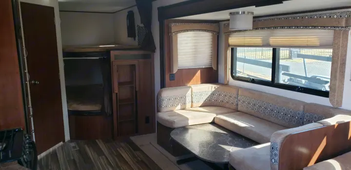 RV rental interior features bunk beds, a sectional couch with a table, and bright windows, offering ample space.. Jayco Jay Flight 2019