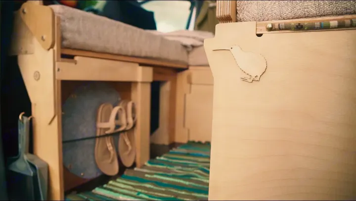 Inside a modern RV rental: clever modular wood interior with storage for shoes & a dustpan, plus a decorative kiwi detail.. Toyota Voxy 2006