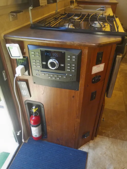 RV rental interior: gas stove, Jensen entertainment system, fire extinguisher, and various controls for mobile living.. Forest River Rockwood Premier 2013