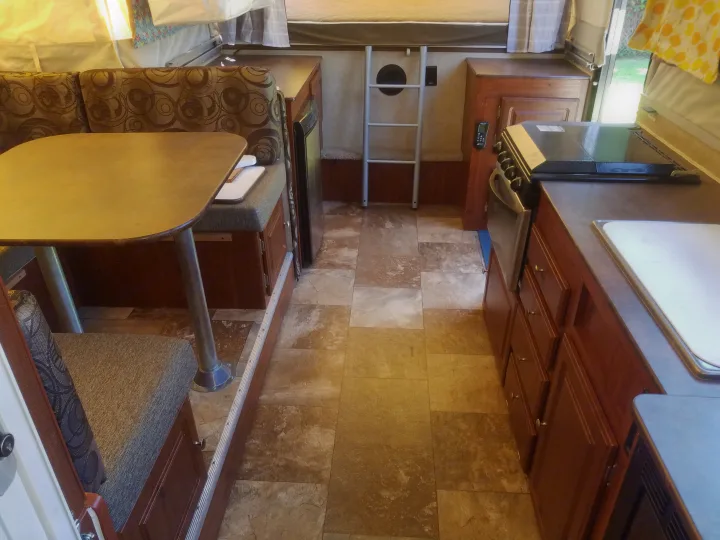 Step inside this RV rental! Features a comfy dinette, full kitchen, and ladder to a sleeping bunk. Ideal for your next adventure.. Forest River Rockwood Premier 2013