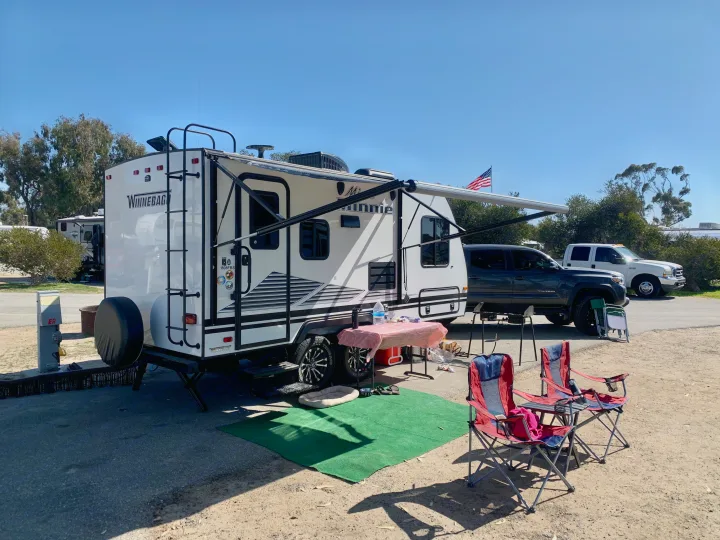 This Winnebago travel trailer is parked and set up at a sunny campsite, perfect for an RV rental getaway.. Other Other 2019