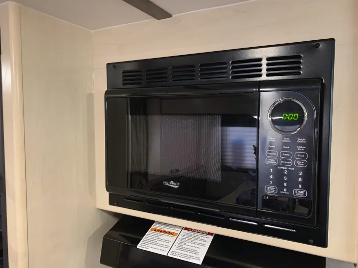 A black High Pointe microwave with a digital display showing 0:00, installed in an RV rental kitchen cabinet.. Other Other 2019