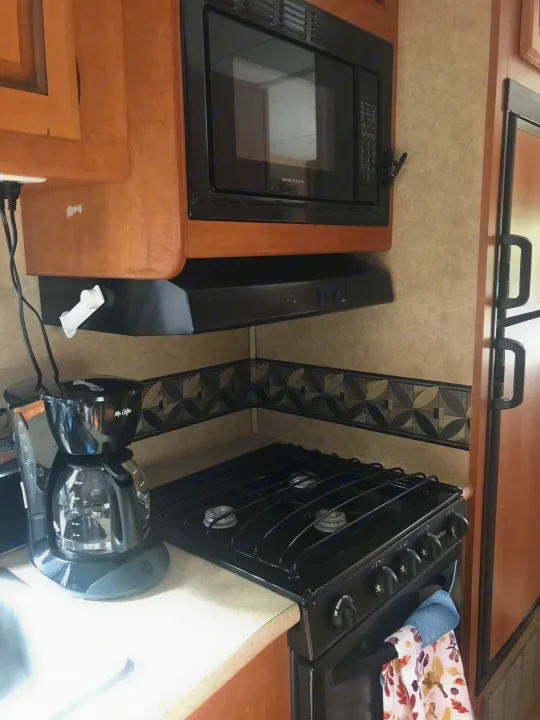 RV rental kitchen: compact space with Hamilton Beach microwave, Mr. Coffee, and Suburban gas cooktop. Cook on the go!. ForestRiver Sunseeker 2012