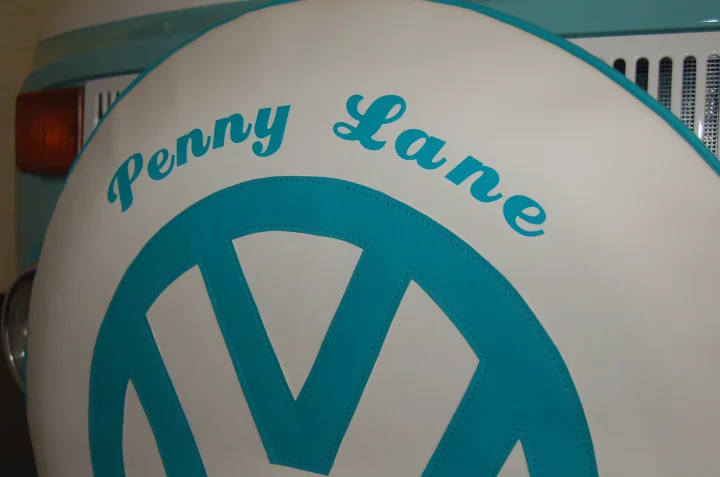 A custom teal & white "Penny Lane" VW bus spare tire cover with the VW logo, a unique detail for your next RV rental.. Volkswagen 2.0L T2 Late Bay 1975