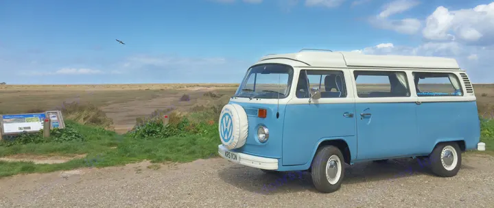 Iconic blue VW campervan, ideal for your next RV rental adventure. Parked by a scenic coastal landscape under a blue sky.. Volkswagen 2.0L T2 Late Bay 1975