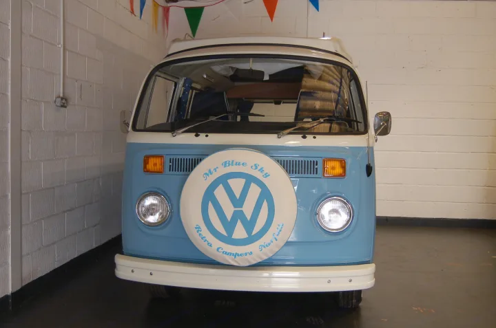 Retro blue & white VW camper van with 'Mr Blue Sky Retro Campers Norfolk' on its front spare tire cover. Perfect RV rental.. Volkswagen 2.0L T2 Late Bay 1975
