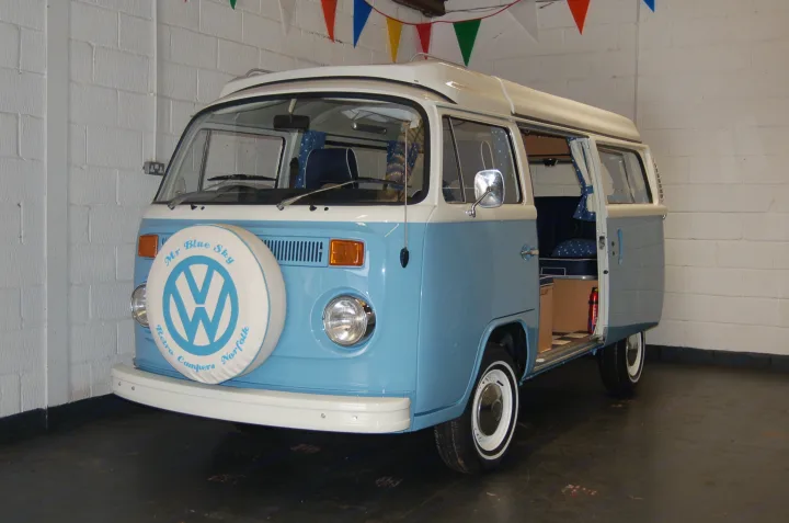 Light blue & white classic VW camper van with pop-top roof, ready for RV rental in Norfolk. Side door open, revealing interior.. Volkswagen 2.0L T2 Late Bay 1975