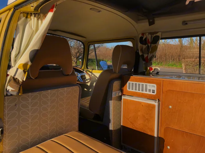 Retro RV rental interior: cozy camper van with custom seating, kitchenette, and vintage curtains. Perfect for road trips!. Volkswagen 2.0L T2 Late Bay 1975