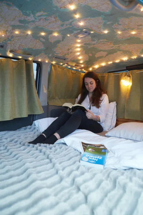 Cozy RV rental interior: woman reading under map ceiling lights, planning New Zealand travel adventures. Perfect comfort!. Toyota Voxy 2007