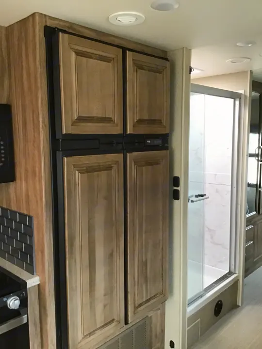 RV rental: View of the kitchen area featuring wood-paneled refrigerator doors, overhead lights, and part of a stove.. Jayco Greyhawk 2022