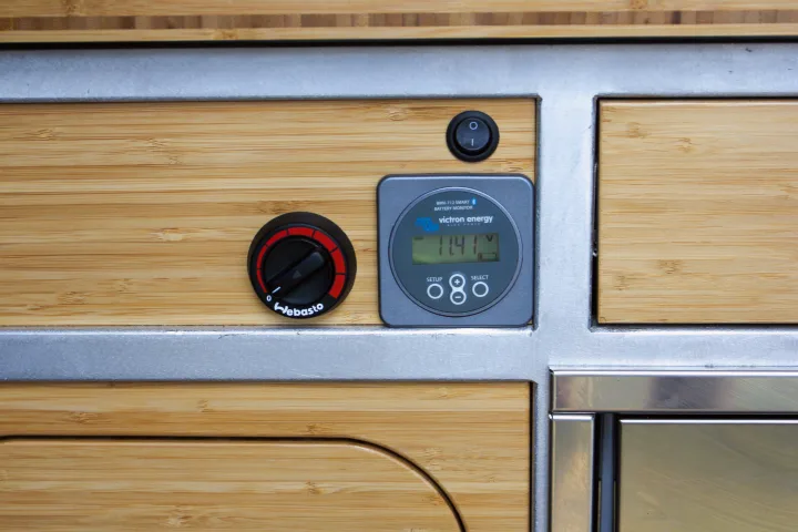 RV rental campervan interior: Webasto heater control, Victron battery monitor (11.4V), and power switch on bamboo panels.. Mercedes-Benz Sprinter 2018