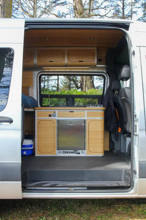 View inside a modern camper van RV rental, showing kitchen, sink, fridge, and bamboo interior.. Mercedes-Benz Sprinter 2018