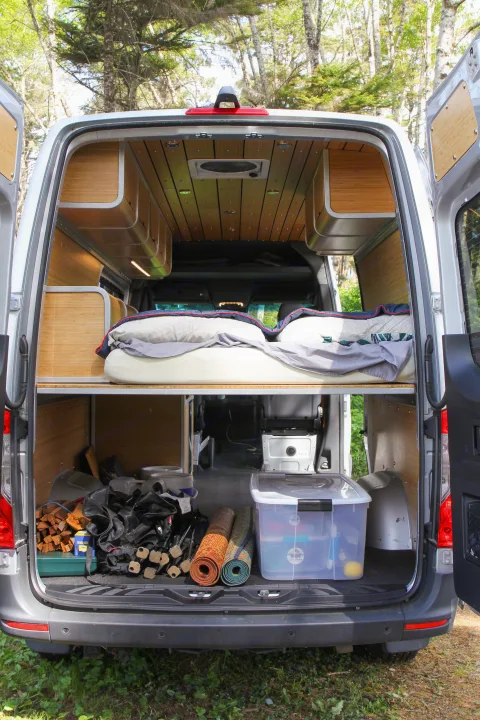 Explore this RV rental's clever interior: a comfortable raised bed, ample under-bed storage, and tasteful wood finishes.. Mercedes-Benz Sprinter 2018