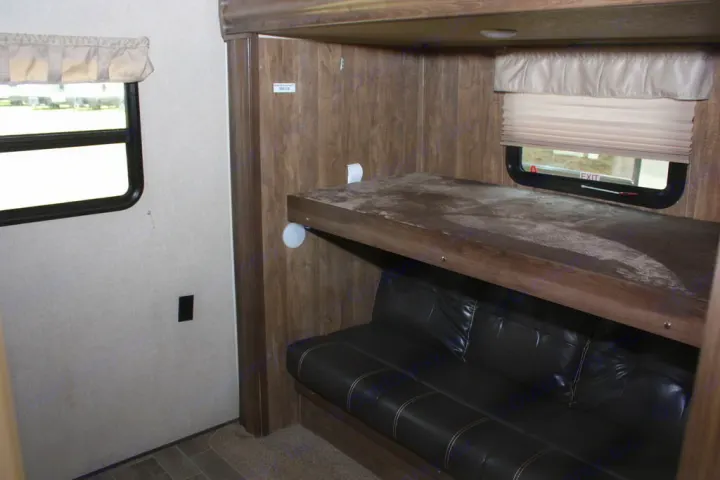 An RV rental interior showing bunk beds (upper bunk and lower convertible couch) and windows. Ideal for travel.. Palomino Puma 2018