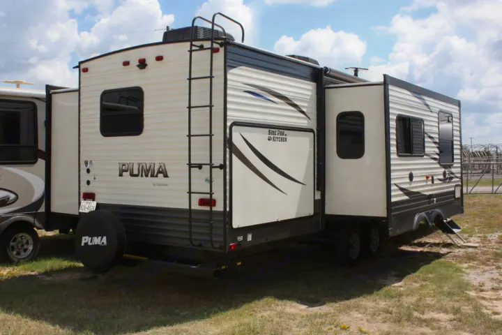 A PUMA travel trailer with slide-outs extended, ready for rv rental. Features include a rear ladder & spare tire.. Palomino Puma 2018