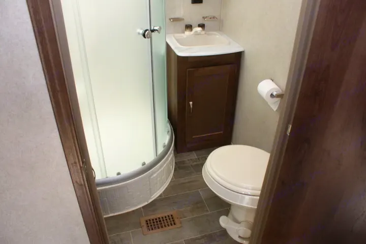 Compact RV bathroom, seen through a doorway, features a corner shower, sink, and toilet for your rv rental.. Palomino Puma 2018