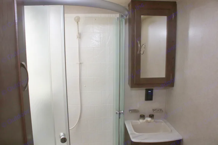 RV rental bathroom showing a compact shower with frosted glass and a small sink vanity with a mirrored cabinet.. Palomino Puma 2018