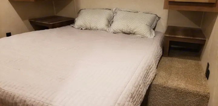 Comfortable RV rental bedroom with queen bed, chevron pillows, and side shelves. Perfect for a good night's sleep on the road.. Palomino Puma 2018