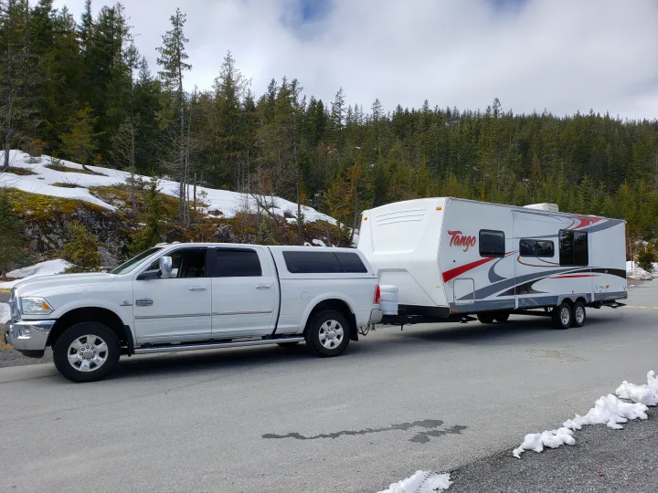 Get ready for your RV rental getaway! A pickup truck tows a Tango travel trailer through a beautiful snowy mountain landscape.. Pacific Coachworks Tango 2010