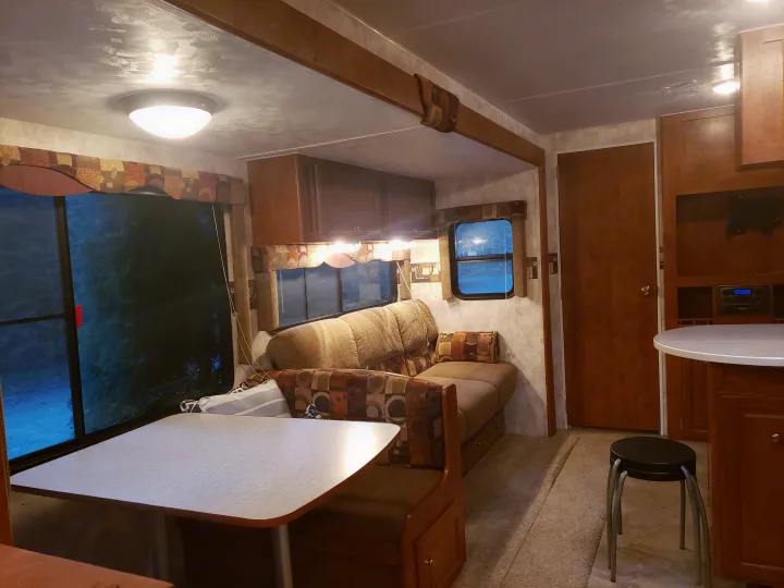 Spacious RV rental interior featuring a comfortable dinette, living area, and kitchen counter with warm lighting for a cozy feel.. Pacific Coachworks Tango 2010