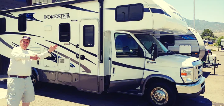 Happy man points to his new white Forester rv rental. This Class C motorhome is ready for travel.. Forest River Other 2018