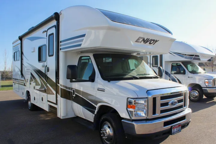 Bright white Class C motorhome with 'ENVOY' branding, excellent for rv rental. Parked on asphalt with another RV behind it.. Jayco Envoy 2018
