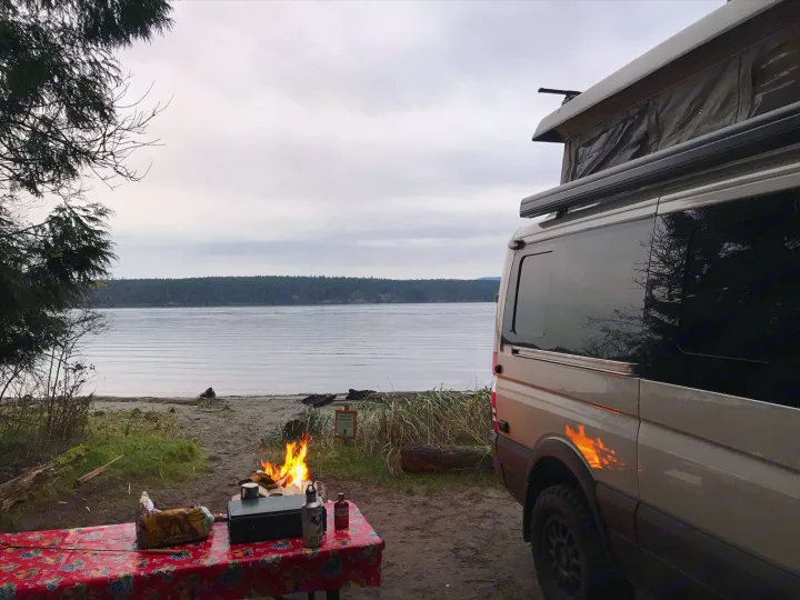 Enjoying an rv rental van by the serene waterfront. Cozy campfire and outdoor cooking make for perfect camping.. Mercedes Sprinter 2018