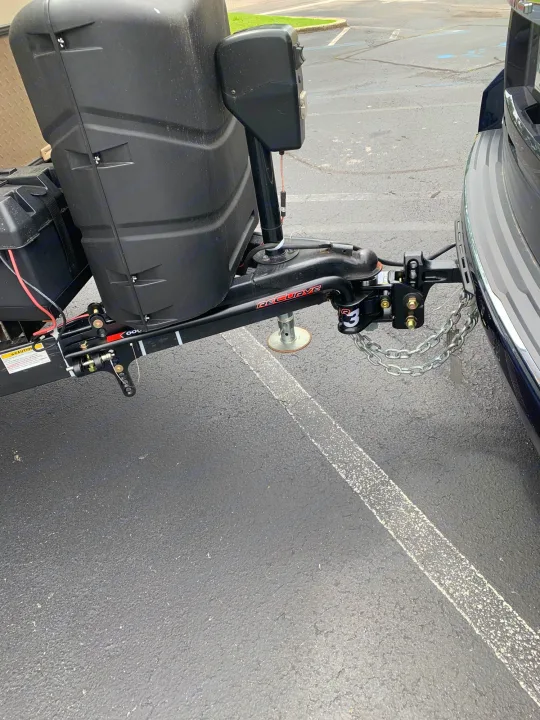 Close-up of an RV rental trailer's towing setup, showing the weight distribution hitch, safety chains, and propane tank cover.. Other Other 2019
