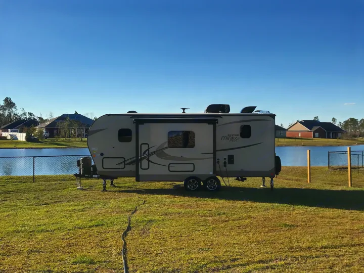 This Rockwood travel trailer, an ideal RV rental, is set up by a calm lake with houses in the background for a scenic getaway.. Other Other 2019