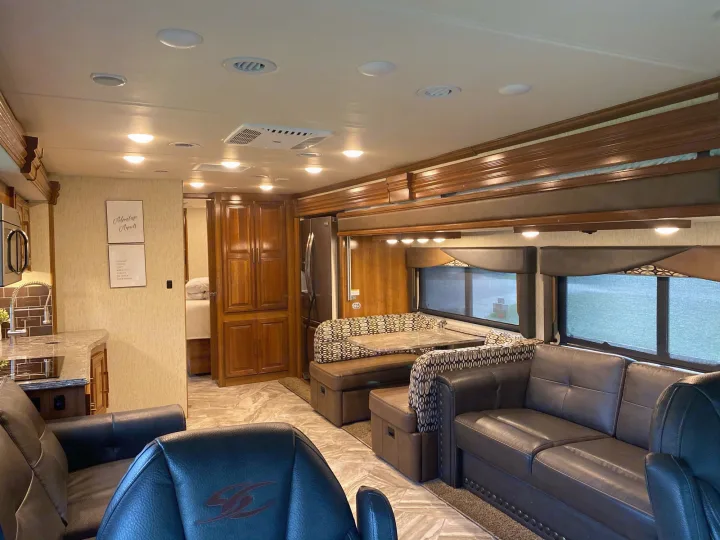 This **RV rental** shows a luxurious living space with leather sofas, dining area, kitchen, and warm lighting, perfect for travel.. Coachmen Sportscoach 2018