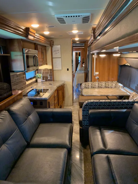 Inside a luxurious RV rental: features a full kitchen, comfy dining booth, and soft leather living area seating.. Coachmen Sportscoach 2018