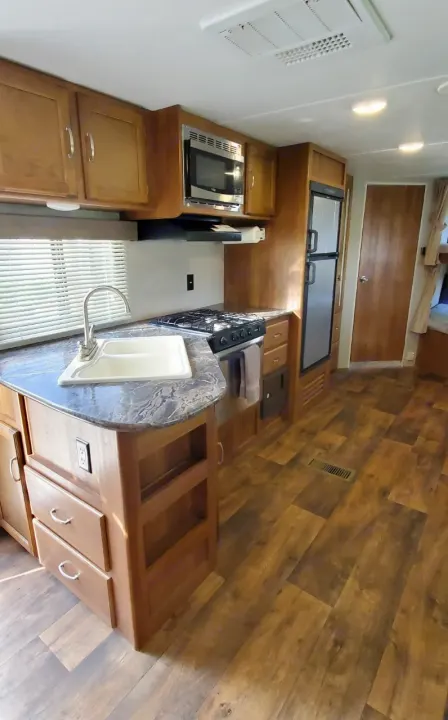RV rental: Full kitchen with double sink, stove, microwave, fridge, and light wood cabinetry on wood-look floors.. Keystone Springdale 2017