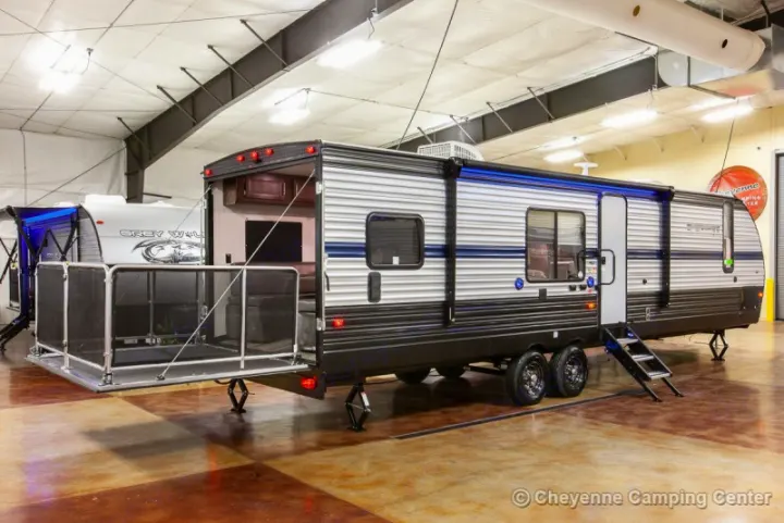 Displayed indoors, this grey and black travel trailer RV, a toy hauler with an open rear patio, is ideal for rv rental.. Forest River Cherokee Grey Wolf 294rr 2020